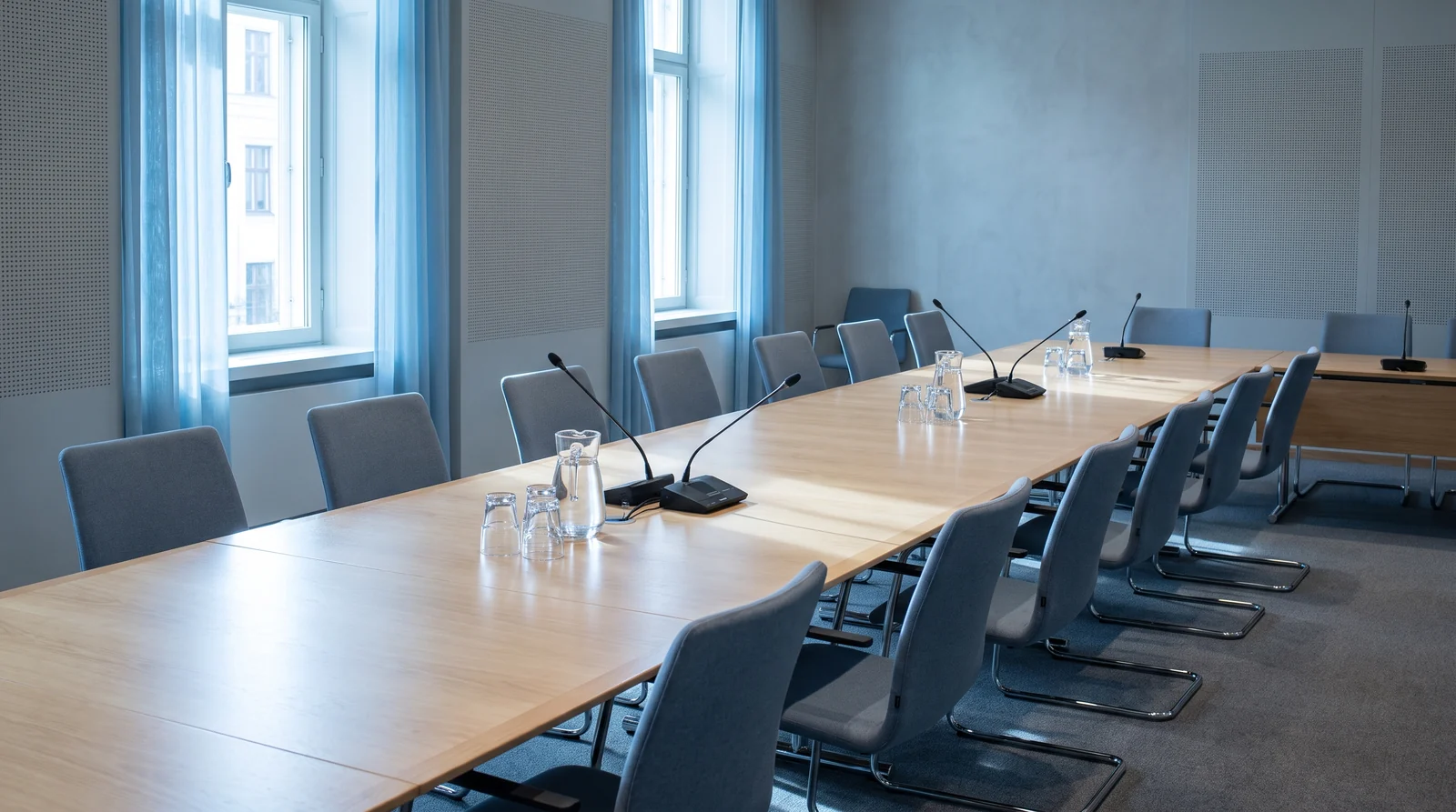 An empty committee room with chairs pushed back from a long table after a meeting.